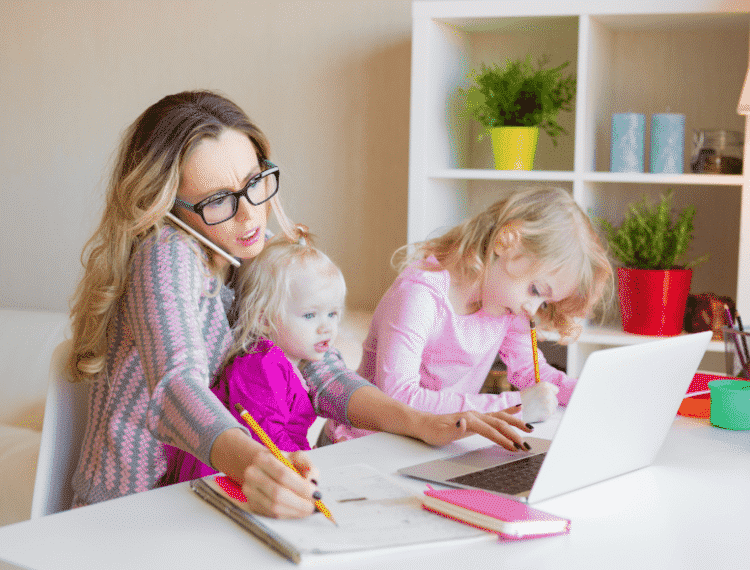 working mother juggling a work call and two young children