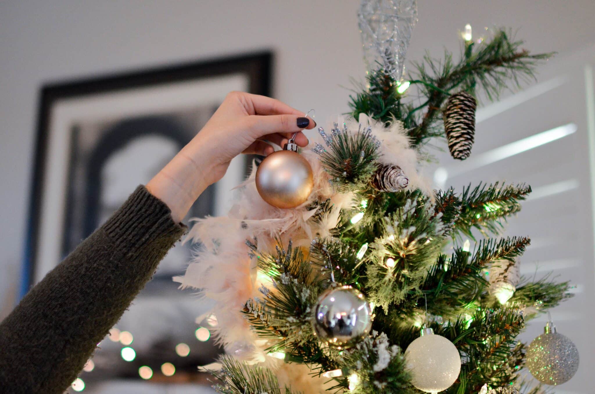 person placing decorations on christmas tree