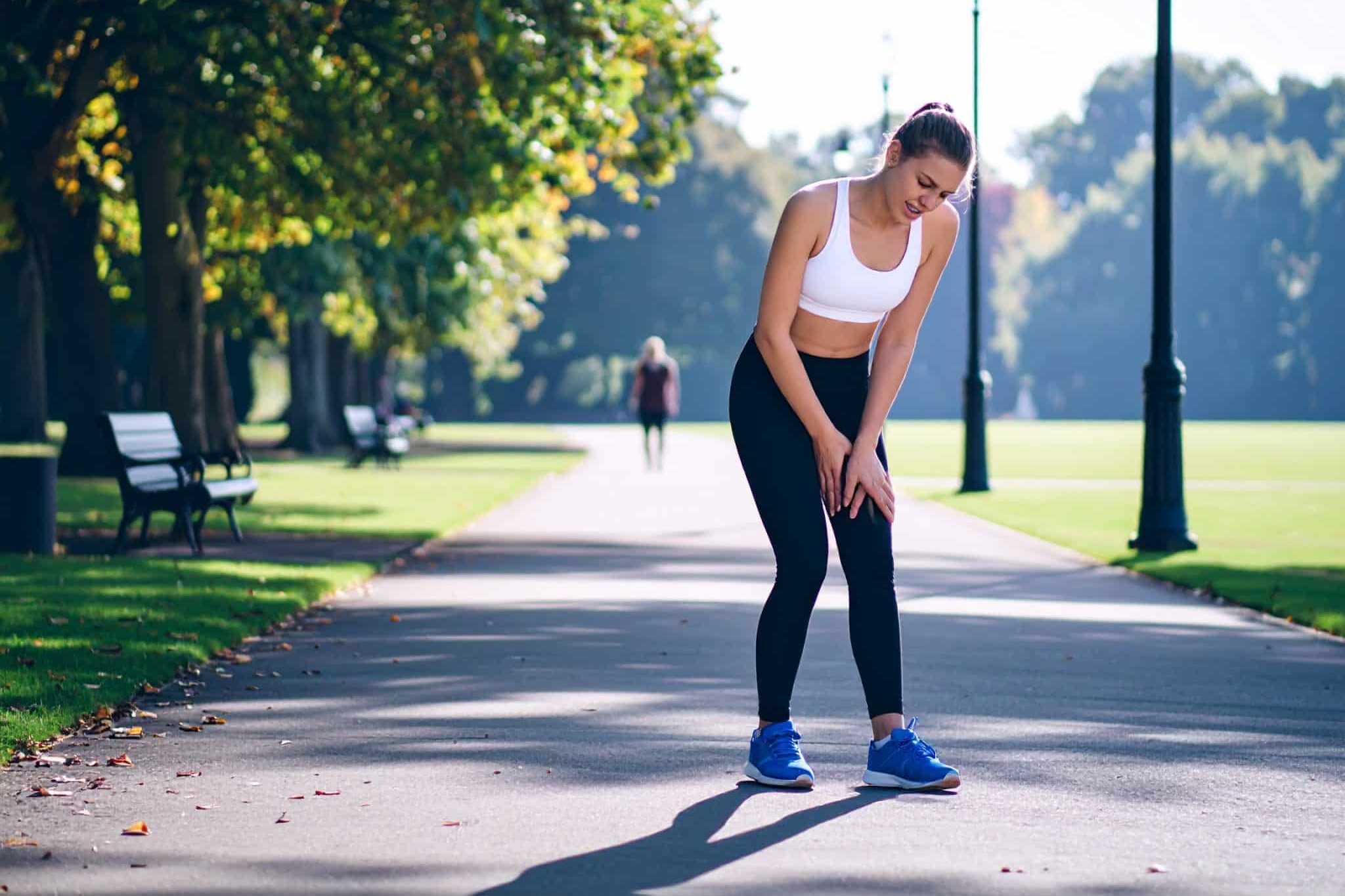 Runner experiencing knee discomfort outdoors.
